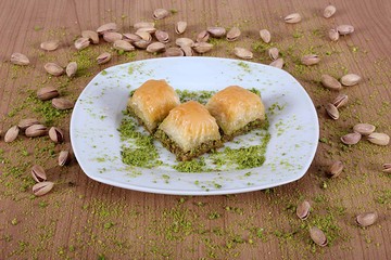 the best turkish baklava pistachios together on a white plate on the plate is filled with green pistachio powder