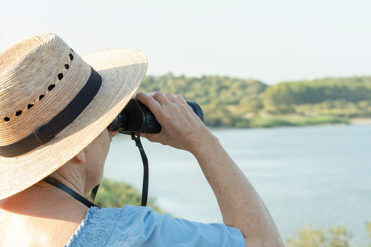 Mujer observa las aves del lago con binoculares