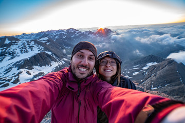 Two friends are a group of hikers having fun and making selfie on the top of the mountain with...