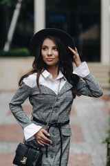 Three quarter length vertical portrait of beautiful girl wearing stylish hat, gray jacket.