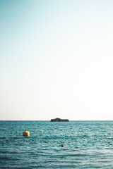 Minimalist seascape with buoys and small island in background - 278451998
