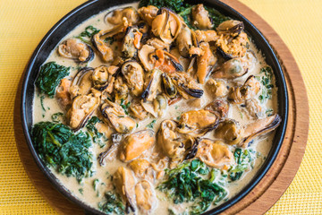 Mussels in a creamy spinach sauce in a pan.