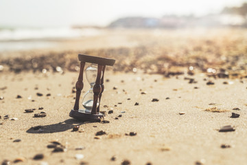 Fototapeta na wymiar Hourglass on the beach, ocean. The concept of transience of time.
