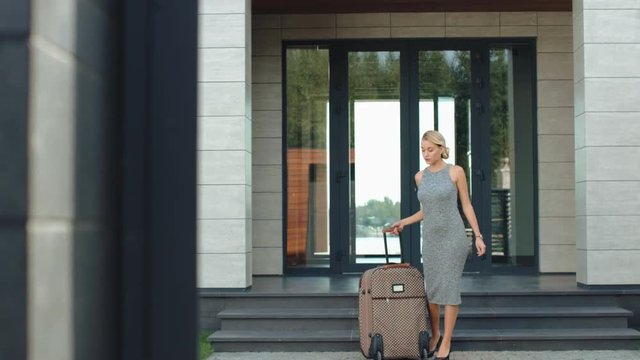 Beautiful woman leaving hotel with luggage. Pretty girl going to vacation.