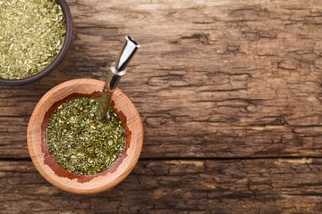 Traditional South American Yerba Mate tea in wooden mate cup with bombilla metal straw serving as a...