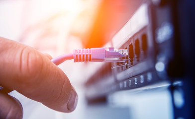 Fototapeta premium Technician connecting network cables to switches. Connecting cables in server cabinet.