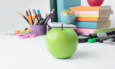 foreground a green Apple on the background of school supplies .photo with copy space - Powered by Adobe