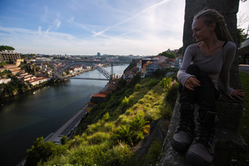Young woman sitting against the background of Dom Luis I bridge, Porto, Portugal.