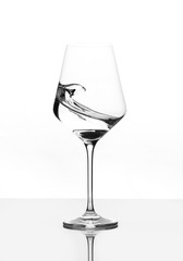 Clear Wineglass with burst of water. Motion against white