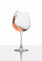 Glass of amber wine with splashes on white table.