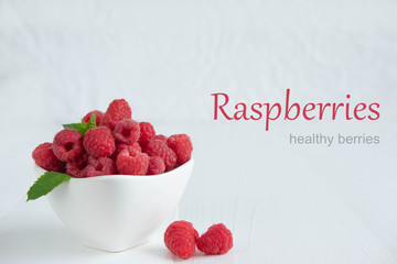 Raspberry berries in a white plate on a light wooden background. Useful berries for health. Photo of raspberry with space for copisapase