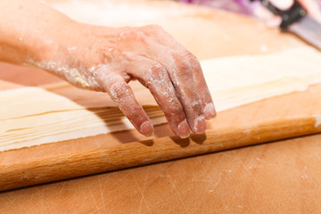 Side view woman's hands make Turkish Ravioli on table. Plates of traditional Turkish food. manti      