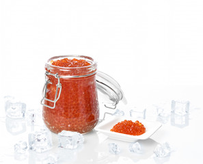 Salmon red caviar in jar can and little plate with ice on table. Sea food