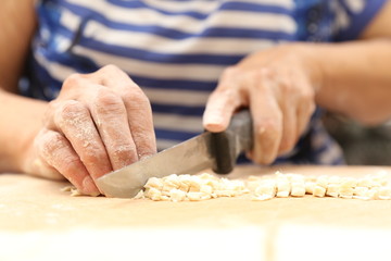 Side view woman's hands make Turkish Ravioli on table. Plates of traditional Turkish food. manti      