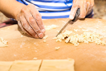 Side view woman's hands make Turkish Ravioli on table. Plates of traditional Turkish food. manti      