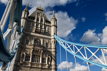 Fototapeta na wymiar Stone tower of Tower Bridge across the Thames river in London with blue and white suspension girders