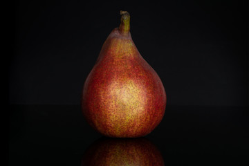 One whole fresh dark red pear anjou isolated on black glass