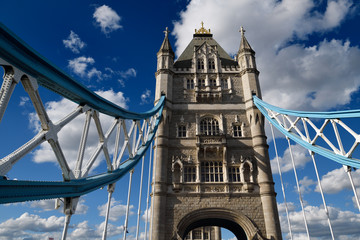 Fototapeta na wymiar Stone towers of Tower Bridge across the Thames river in London with blue and white suspension girders