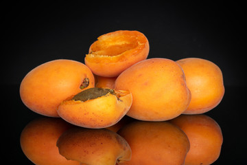 Group of three whole two halves of fresh deep orange apricot with a stone isolated on black glass