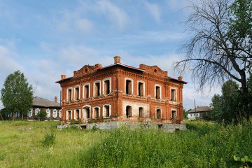 Abandoned historical residential house with courtyard overgrown with grass. Village of Visim, Sverdlovsk region, Urals, Russia