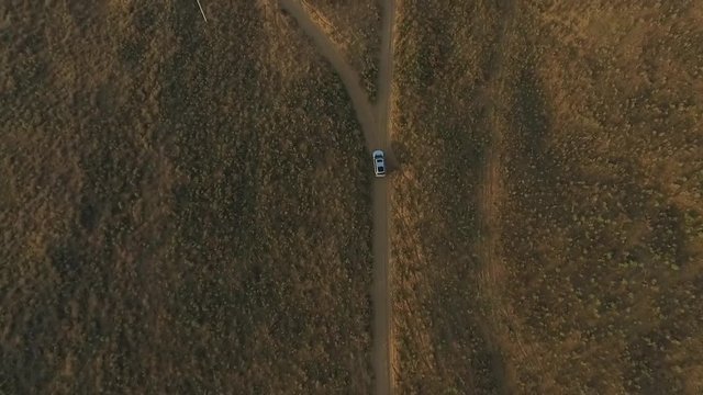 Top down view on big silver SUV drive in the steppe or field on road.
