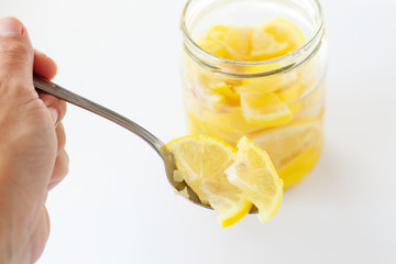 eating yellow lemons to increase immunity, fresh sliced lemons in a jar filled with sugar on white background 