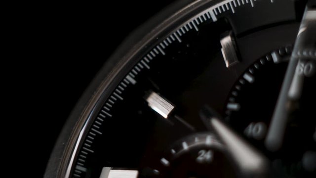 Wrist watch time lapse close up on a black background. white clock hands