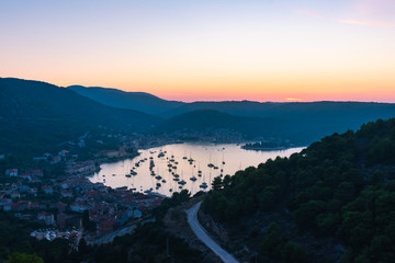 Obraz premium Landscape and top view of the old historic city of Vis and the harbor with moored sailing boats and yachts during a beautiful sunset in summer, Vis island, Croatia, Europe