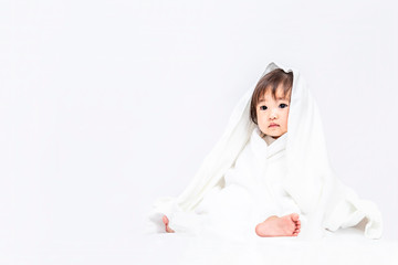 バスタオルを被り見つめる女の子の赤ちゃん。育児,リラックス,幸福,イメージ