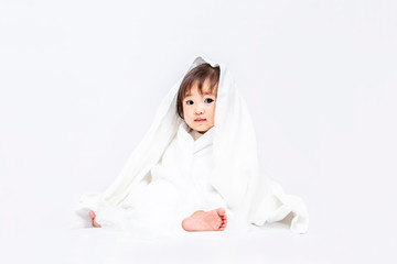 バスタオルを被りカメラ目線の女の子の赤ちゃん。育児,リラックス,幸福,イメージ
