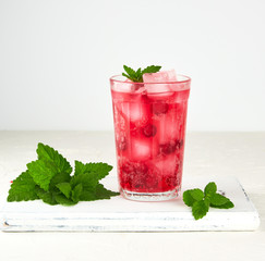 summer refreshing drink with berries of cranberries and pieces of ice in a glass