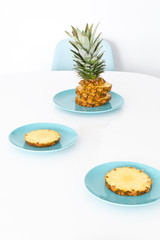 Sliced, juicy, ripe pineapple on turquoise plates. Everything on the white table. A minimalistic shot.