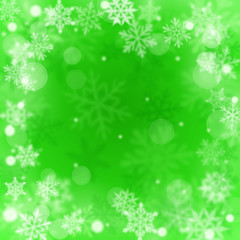 Fototapeta na wymiar Christmas blurred background of complex defocused big and small falling snowflakes in green colors with bokeh effect