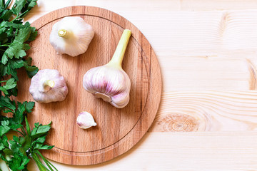 High point view on three pieces fresh garlic on wooden plate