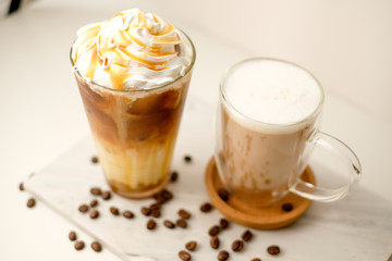 Ice coffee in the glass topped whipping cream with coffee beans. Cold summer drink on wooden background and copy space. Advertising for caramel mocha and chocolate beverage for the cafe.