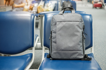gray business backpack on seat at the interior of airport terminal. Business and Travel concept