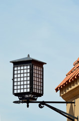 Fototapeta na wymiar Black and white cast iron cuboidal street lantern characteristic of Warsaw Old Town, Poland