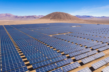 Aerial view of hundreds solar energy modules or panels rows along the dry lands at Atacama Desert,...
