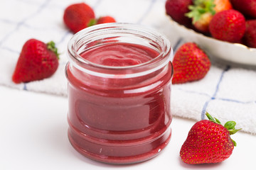 Strawberry jam in a jar on white kitchen towel