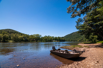 A boat tied up to the shoreline of the Allegheny river in Warren County, Pennsylvania, USA on a summer day