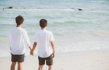 Asian gay couple holding hands together on the beach with relax and leisure in summer, LGBT homosexual legal two man happy and romantic in vacation, relationship sex lover concept.