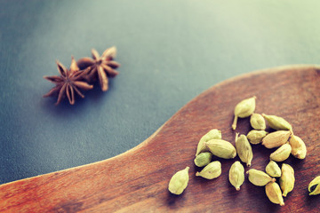 Dry Star anise and cardamom on a brown wooden spatula. Natural food spices and seasonings. Tasty eating. Close-up. selective focus