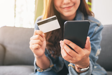 An asian woman using credit card for purchasing and shopping online on mobile phone