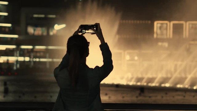 Happy young girl makes video of fountains and illuminations