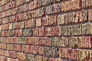 Side angle view of a multi color textured brick wall background in primary colors of red, blue, and yellow