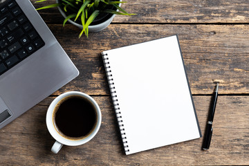 empty notebook with coffee and computer on wooden table ,top view