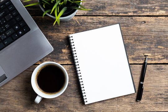 empty notebook with coffee and computer on wooden table ,top view