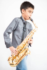 Naklejka premium Little asian musician boy playing saxophone instrument