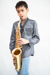 Fototapeta premium Little asian musician boy playing saxophone instrument