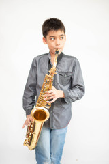 Little asian musician boy playing saxophone instrument